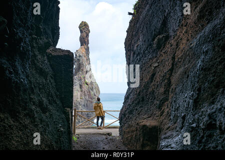 Girl looking at Ribeira da Janela islet entre une grotte à Madère Banque D'Images