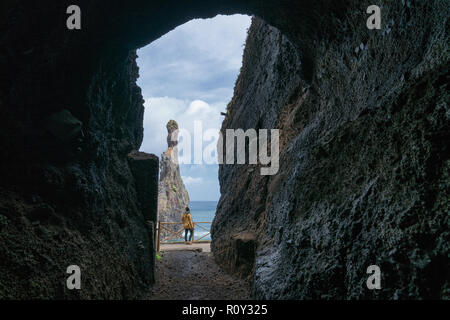 Girl looking at Ribeira da Janela islet entre une grotte à Madère Banque D'Images