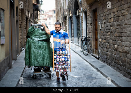 Florence, Italie - 31 août 2018 :, vendeur de rue, le vendeur à Firenze Mercato di San Lorenzo, marcher dans l'allée étroite, holding souven Banque D'Images