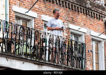 New Orleans, USA - 22 Avril 2018 : Local homme heureux sur balcon avec de nombreux festival de Mardi gras colorés perles collier accroché au centre-ville de ville historique Banque D'Images