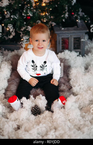 Joli bébé avec Virginie sur jersey assis dans la neige artificielle à Ch Banque D'Images