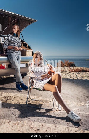 Smiling woman chilling tandis que la consommation de bière près de mobile home avec son homme Banque D'Images