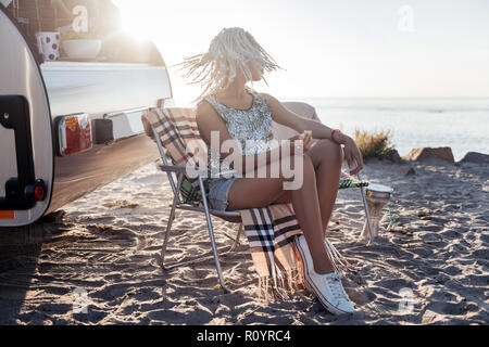 Le port de jeans femme Slim pantalon blanc et chaussures assis près de maison mobile Banque D'Images