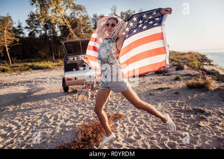 Femme portant des jeans shorts et baskets tenant son drapeau voyageant avec elle Banque D'Images