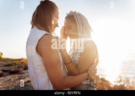 Jeune femme élégante avec des dreadlocks hugging her strong bel homme Banque D'Images