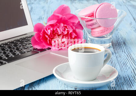 Bouquet de belles pivoines, tasse avec du café et de l'ordinateur sur table lumineuse Banque D'Images