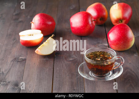 Tisane dans le verre et pommes sur table en bois Banque D'Images
