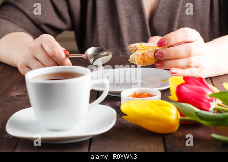 Le petit-déjeuner gratuit. Femme mange du pain et de la confiture et de boire le thé Banque D'Images