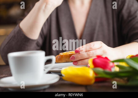 Le petit-déjeuner gratuit. Femme mange du pain et de la confiture et de boire le thé Banque D'Images