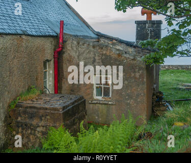 Maison abandonnée sur la côte de l'île des Hébrides avec cheminée rouge vif Banque D'Images