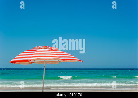 Mon rouge et blanc à rayures parasol se dresse comme un symbole d'un style de vie et la culture sur la plage de Surfer's Paradise Beach à la Côte d'or. Banque D'Images