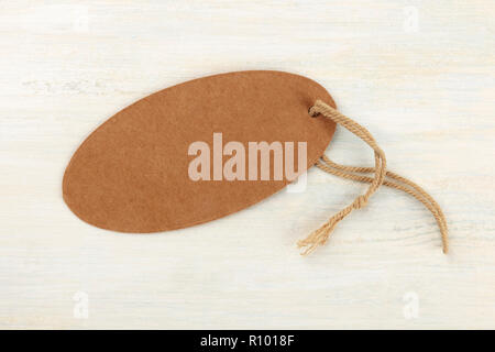 Une photo d'une étiquette en papier craft marron ovale ou étiquette de prix, tourné par le haut sur un fond en bois clair avec copie espace Banque D'Images