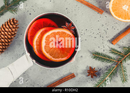 Vue de dessus sur un pot avec boisson traditionnelle de Noël vin chaud avec des tranches d'orange, l'anis et des bâtons de cannelle parmi les décorations d'hiver. Banque D'Images