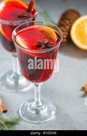 Deux glassses avec Noël hiver traditionnel vin chaud avec des tranches d'orange, l'anis et des bâtons de cannelle parmi les décorations d'hiver. Banque D'Images