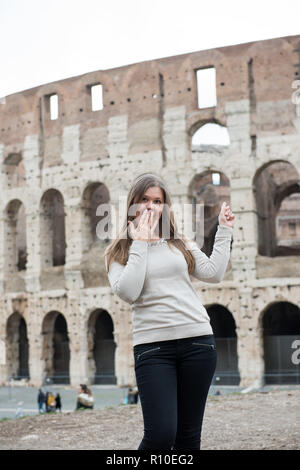 Smiling girl wearing white pull devant le Colisée, Rome, Italie, se demandant, l'air surpris Banque D'Images