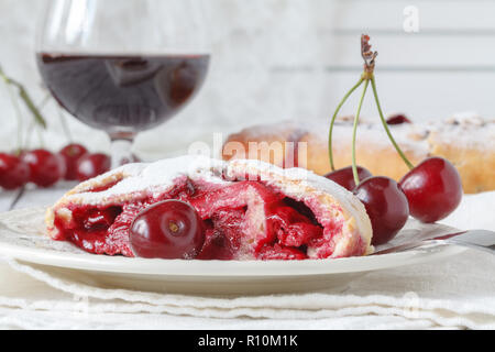 Tourte aux cerises et de la crème dans un plat, serviette avec une cuillère sur un fond de panneaux de bois Banque D'Images