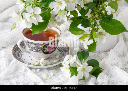 Tasse de thé sur la table de bois et Apple Blossom. L'heure du thé concept. Petit-déjeuner tasse de thé servi avec des fleurs. Banque D'Images