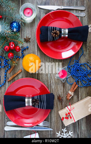 Réglage de la table de Noël. Plaque rouge, fourchette, couteau, tangerines, bougie, serviette, cadeaux branche d'un arbre de Noël sur un fond de bois. Noël N Banque D'Images