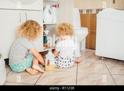 Les enfants sans surveillance jouer tranquillement à une salle de bains privative avec produits chimiques ménagers dangereux. Pour la sécurité à la maison concept. Garder hors de la portée des enfants. Banque D'Images