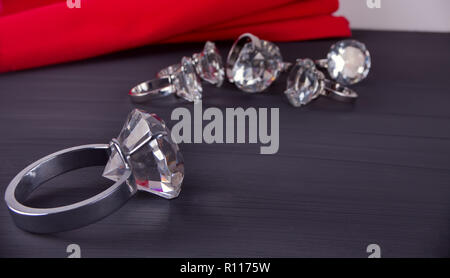 Grand géant anneau de diamant sur la table. Dans l'arrière-plan un tas de joints toriques et serviette rouge Banque D'Images