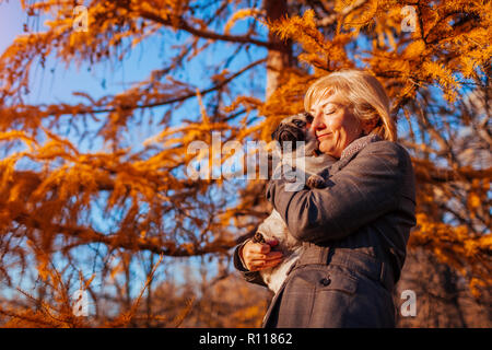 Balades maître chien pug in autumn park. Happy woman hugging pet. Banque D'Images