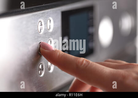 Close up femme main tout en utilisant le micro-ondes dans sa cuisine Banque D'Images