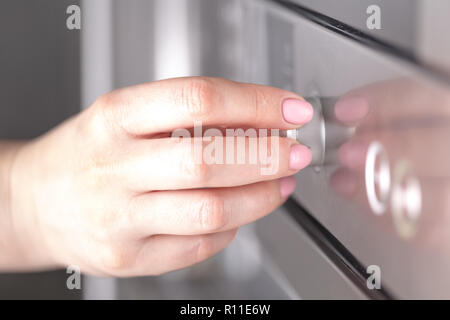 Close up femme main tout en utilisant le micro-ondes dans sa cuisine Banque D'Images