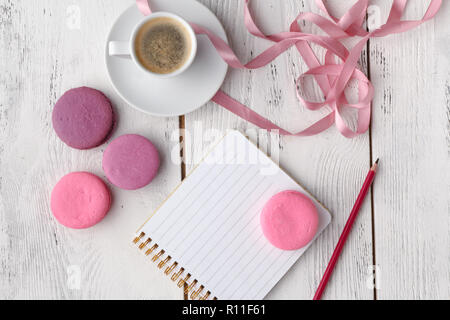 Café, gâteau macaron, propre ordinateur portable, lunettes et rose fleur sur table à partir de ci-dessus. Travail des femmes 24. Petit déjeuner agréable. Mise à plat de style. Banque D'Images