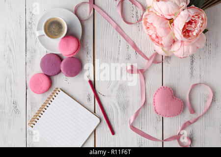 Café, gâteau macaron, propre ordinateur portable, lunettes et rose fleur sur table à partir de ci-dessus. Travail des femmes 24. Petit déjeuner agréable. Mise à plat de style. Banque D'Images