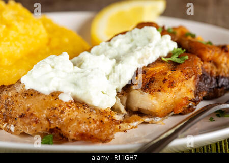 Le poisson frit avec de la polenta et sauce à l'ail sur platine - vue rapprochée Banque D'Images