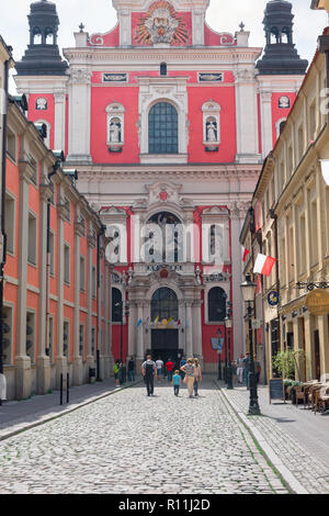 Rue de la ville de Poznan, voir des gens dans la vieille ville de Poznan à marcher en direction de la façade baroque de l'église paroissiale de saint Stanislas, en Pologne. Banque D'Images