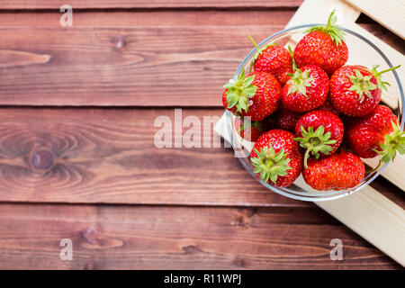 Un tas de jus de fraises mûres dans un bol sur la table en bois.de fraises fraîches dans panier, fruits fraîchement récoltés sur farmer market.L'alimentation saine pour le petit déjeuner et snack.Copy space Banque D'Images