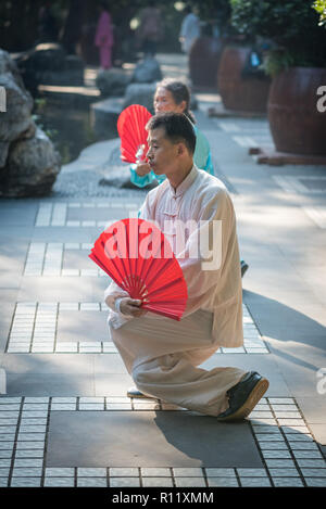 Chengdu, province du Sichuan, Chine - 31 Oct 2018 : man and woman practicing Tai Chi avec red fans le matin dans le parc du peuple. Banque D'Images