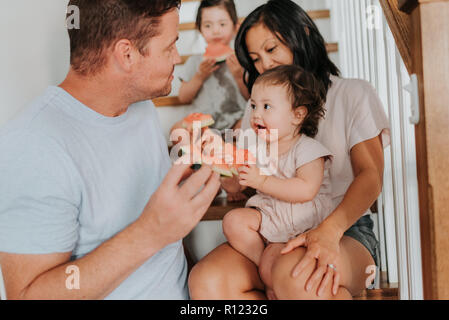 Les parents bénéficiant d'pastèque à ses filles sur escaliers Banque D'Images