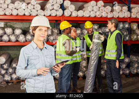 La femme comme un apprenti logistique dans le centre d'expédition et l'employé de l'entrepôt à l'arrière-plan Banque D'Images