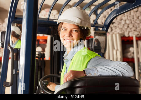 Jeune femme en formation de conducteur de chariot élévateur à l'entrepôt dans le centre logistique Banque D'Images