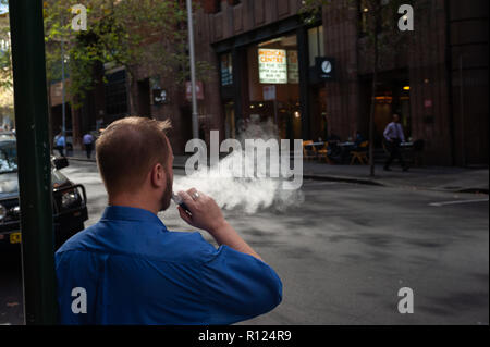 10.05.2018, Sydney, Nouvelle-Galles du Sud, Australie - Un homme est un fumeur cigarette électronique / e-cigarette sur une rue dans le quartier des affaires de Sydney. Banque D'Images