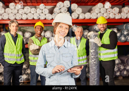 Groupe des travailleurs d'entrepôt et de jeune femme comme apprenti avec tablet PC in warehouse Banque D'Images