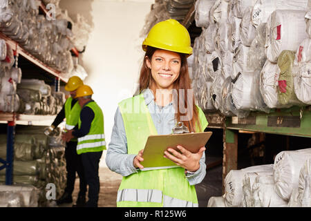 Jeune femme de la logistique comme apprenti à l'entrepôt spécialiste avec des presse-papiers dans l'entrepôt Banque D'Images