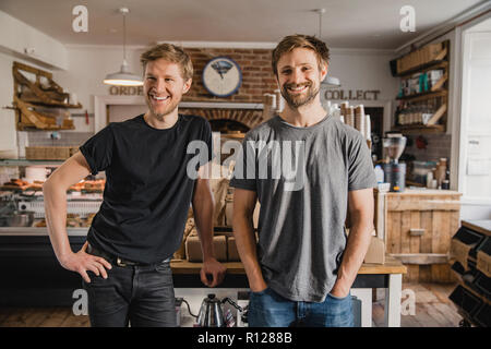Portrait de deux fiers propriétaires de café à l'intérieur permanent de la petit café qu'ils possèdent. Banque D'Images