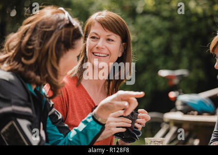 Petit groupe de cyclistes de sexe féminin sont assis dans le coin salon extérieur d'un café. Tey profitent de quelques rafraîchissements à mesure qu'ils prennent une pause. Banque D'Images