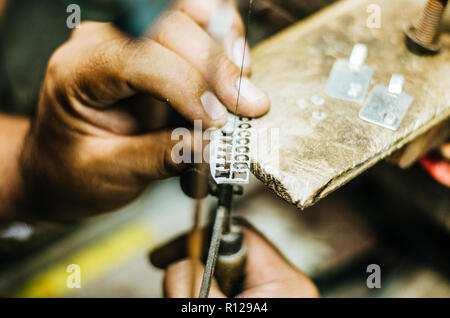 Man's hands goldsmith travailler sur une pièce d'argent avec une scie à métaux sur la table de travail, Close up, choisis focus, réduire la profondeur de champ Banque D'Images