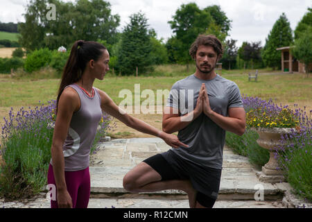 Enseignement professeur de yoga femme jeune homme yoga Yoga à jardin, posture de l'arbre Banque D'Images