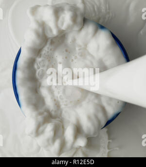 On verse le lait de déborder dans bol Banque D'Images
