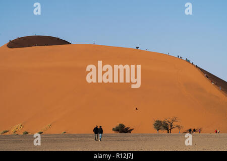 Touristes escaladant les dunes de sable, Sossusvlei, désert du Namib, Parc du Namib-Naukluft, Namibie Banque D'Images