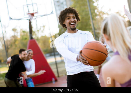 Couple multiracial jouant au basket-ball sur une cour au jour outumn Banque D'Images