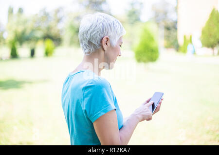 Portrait of senior woman en vêtements de sports de plein air à l'aide de smart phone Banque D'Images