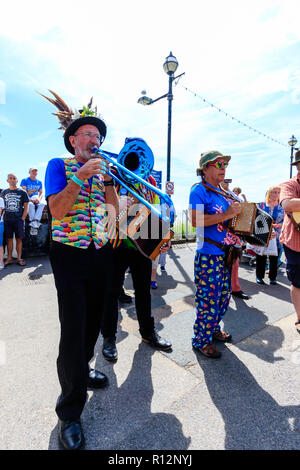 Festival de la semaine folklorique de Broadstairs. Senior male wearing hat avec plumes, musicien folk, debout à l'extérieur avec d'autres, tout en jouant un trombone bleu. Banque D'Images