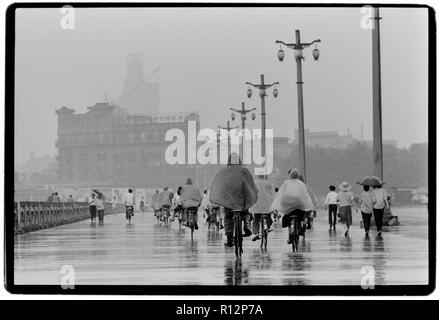 Chine Shanghai quelques jours après le massacre de la place Tiananmen en juin 1989. Les numérisations effectuées en 2018, hommes et femmes sur les bicyclettes à Shanghai sous la pluie. Banque D'Images