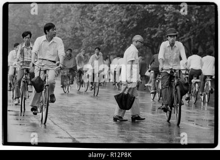 Chine Shanghai quelques jours après le massacre de la place Tiananmen en juin 1989. Les numérisations effectuées en 2018, hommes et femmes sur les bicyclettes à Shanghai sous la pluie. Banque D'Images